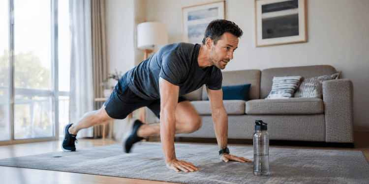 An adult performing mountain climbers in a high plank position, one knee driven toward the chest