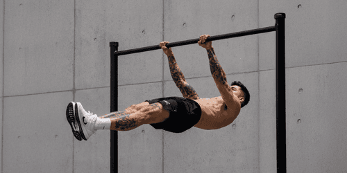 Athlete demonstrating an advanced calisthenics bodyweight exercise on a pull-up bar